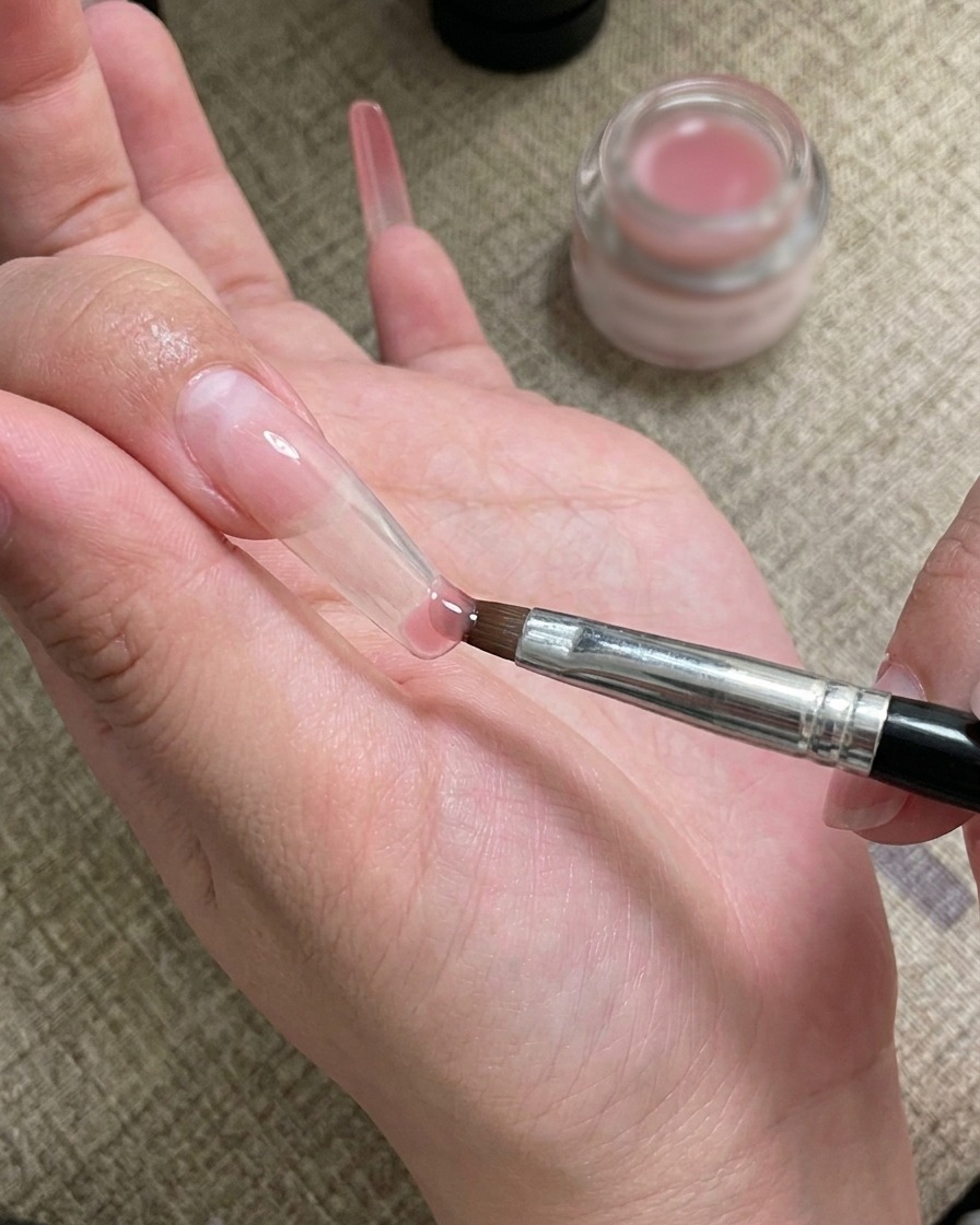 Un pennello per nail art applica e sfuma il gel sulla punta dellunghia.