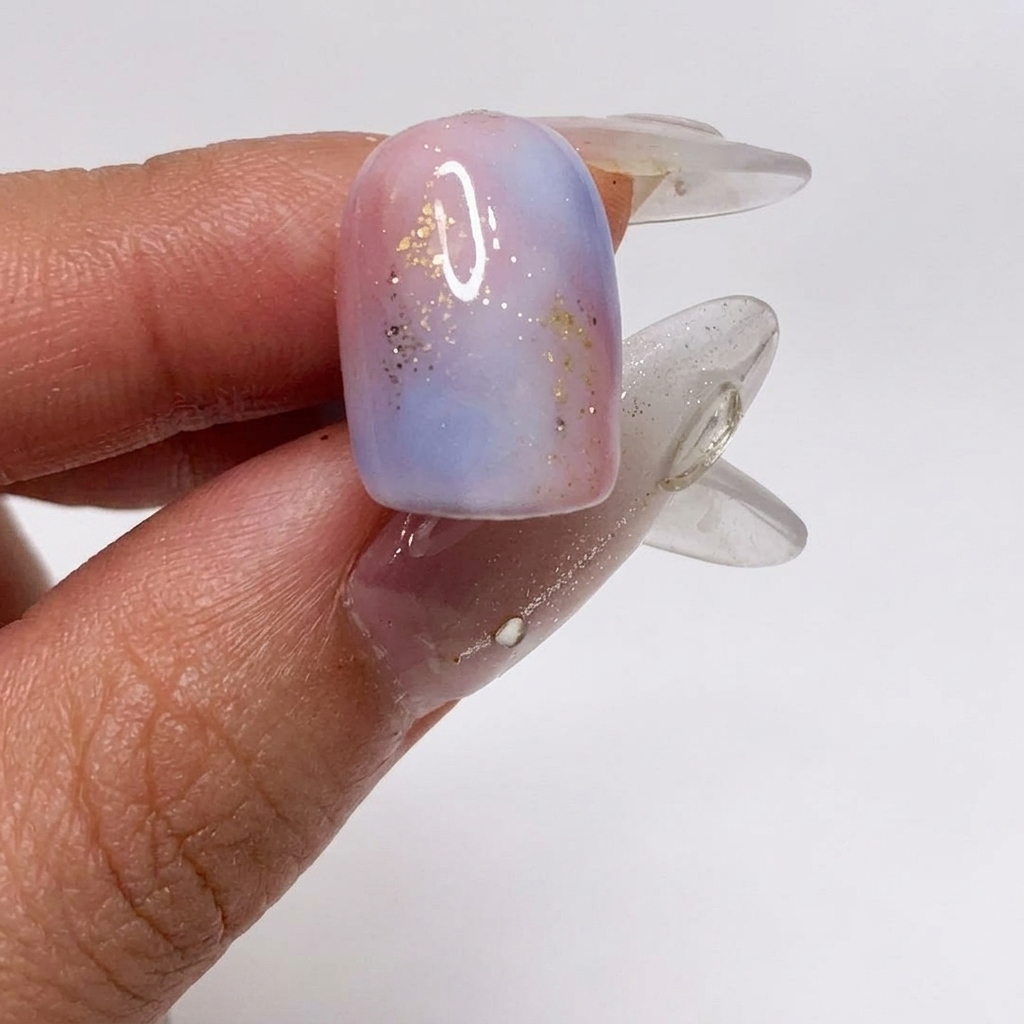 Un pennello che applica un top coat opaco sopra lunghia gradient testurizzata e glitterata.
