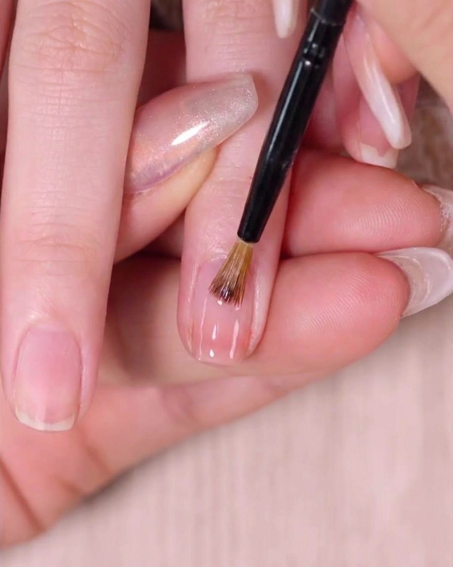 Un pennello da nail art che sfuma delicatamente lo smalto vicino alla cuticola.