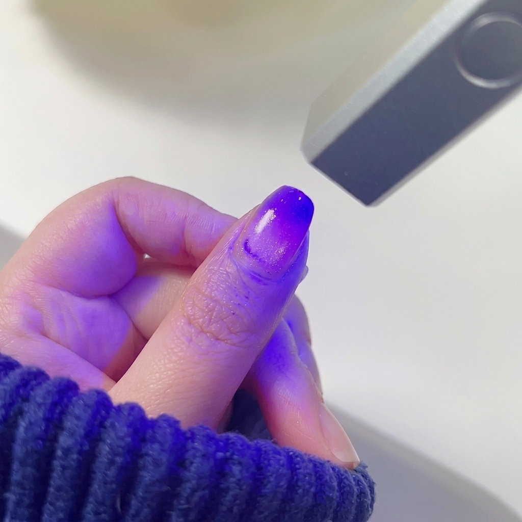 Ununghia con sfumatura rosa e viola in asciugatura sotto la luce di una mini lampada LED.