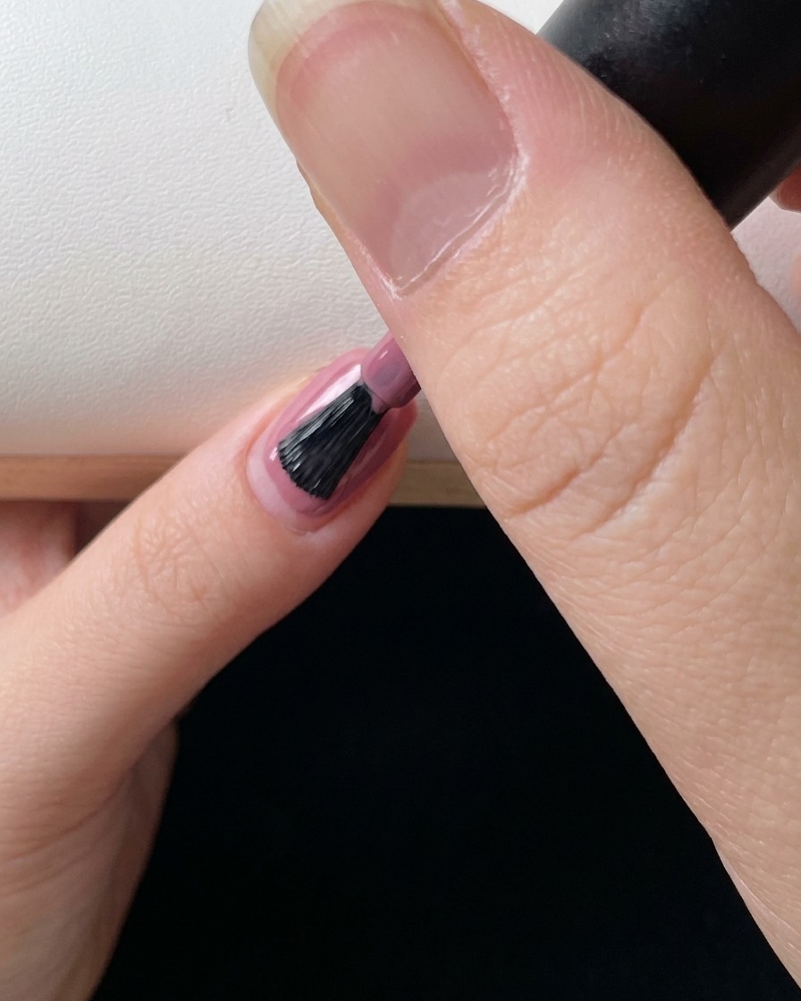 Primo piano di un pennello che applica un ultimo strato di gel rosa per perfezionare leffetto sfumato.