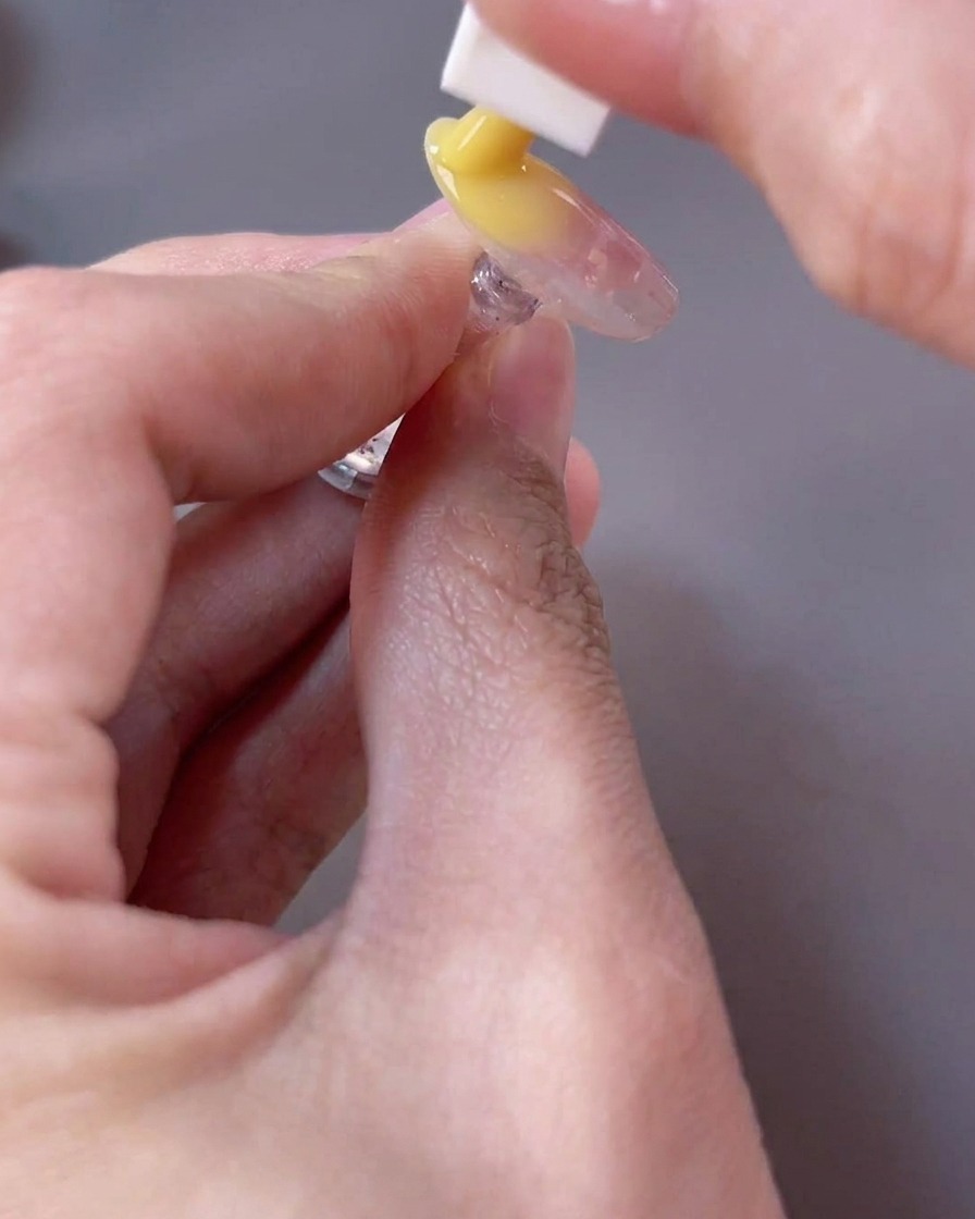 Una spugnetta che applica un gel giallo brillante sul bordo libero dellunghia per creare un effetto gradiente.