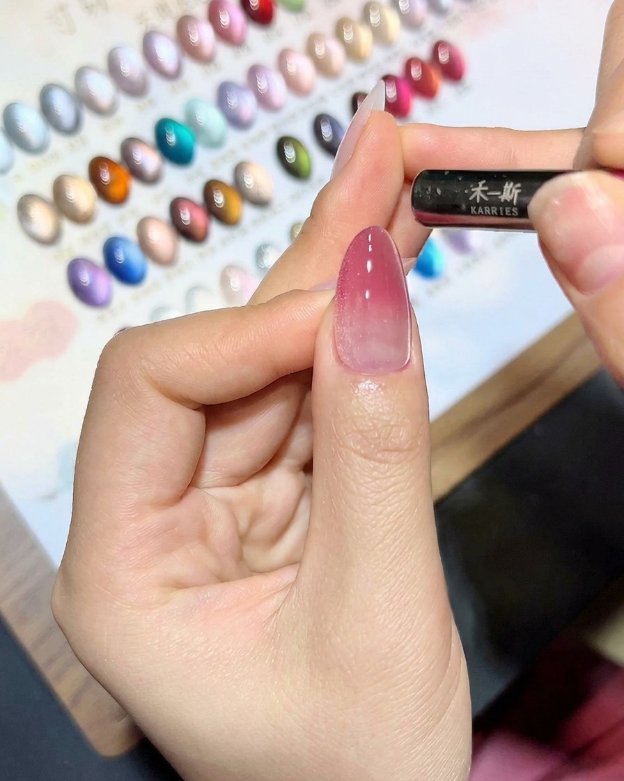 Un magnete tenuto vicino a ununghia ricoperta di gel cat-eye per creare una linea luminosa.