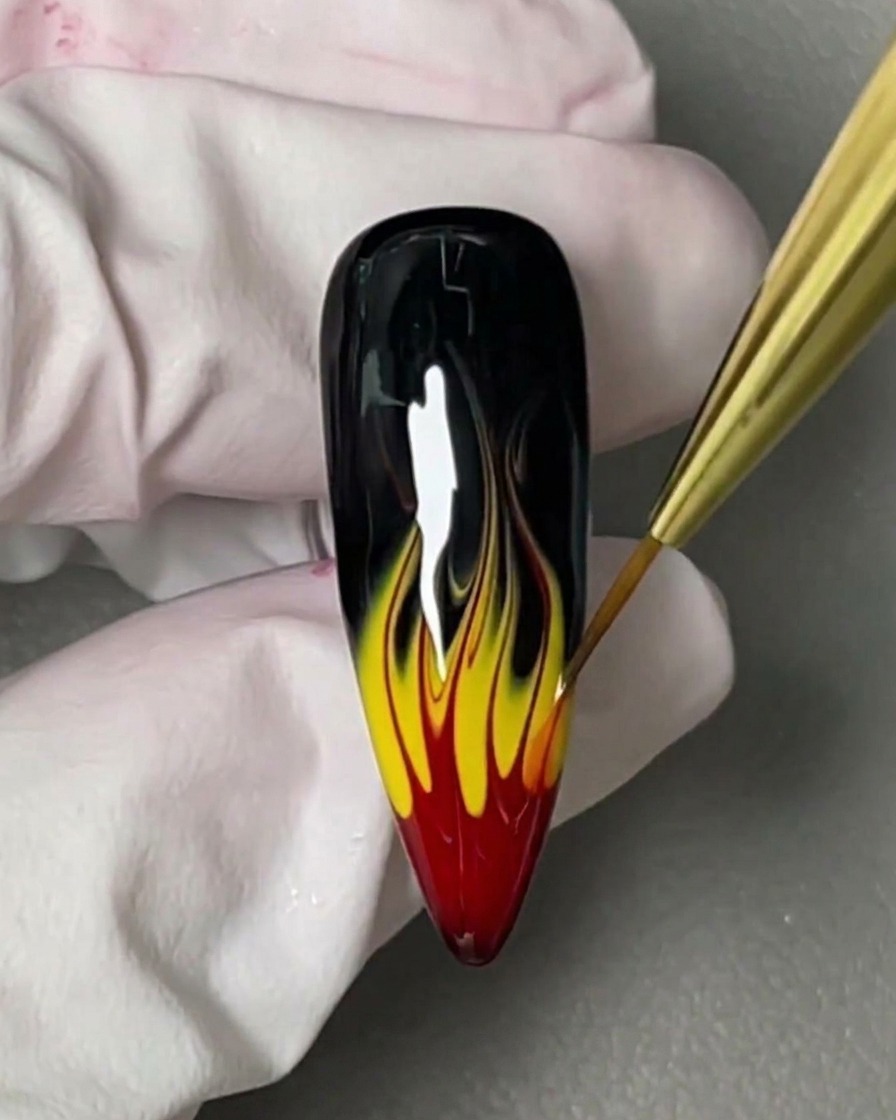 Un piccolo pennello applica un blooming gel trasparente e viscoso su ununghia nera lucida.