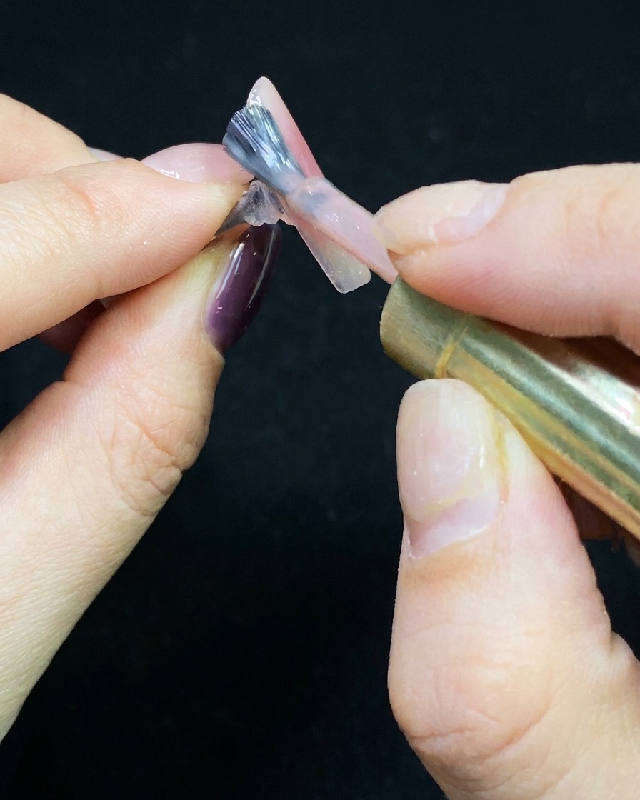 Un pennello che stende uno strato sottile di gel nude su una tip trasparente.