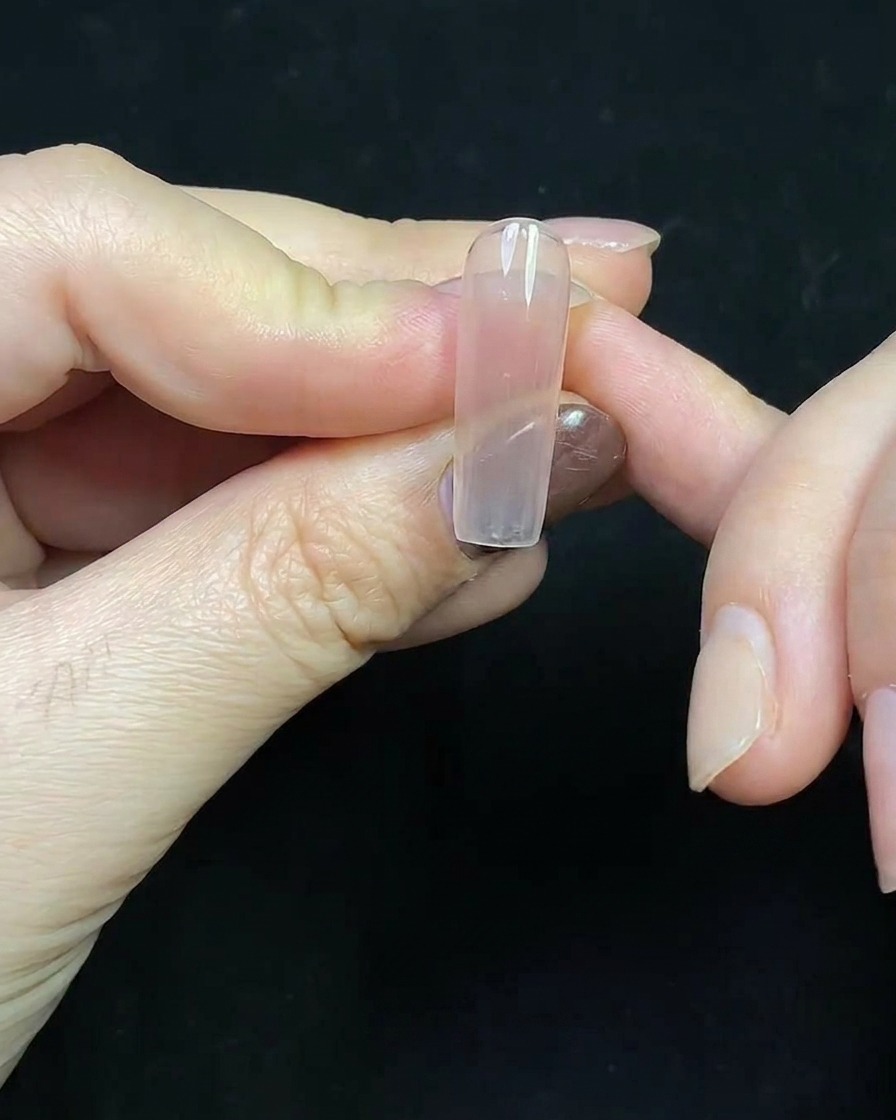 Primo piano di una french tip rosso intenso dipinta su unestensione ungueale trasparente.