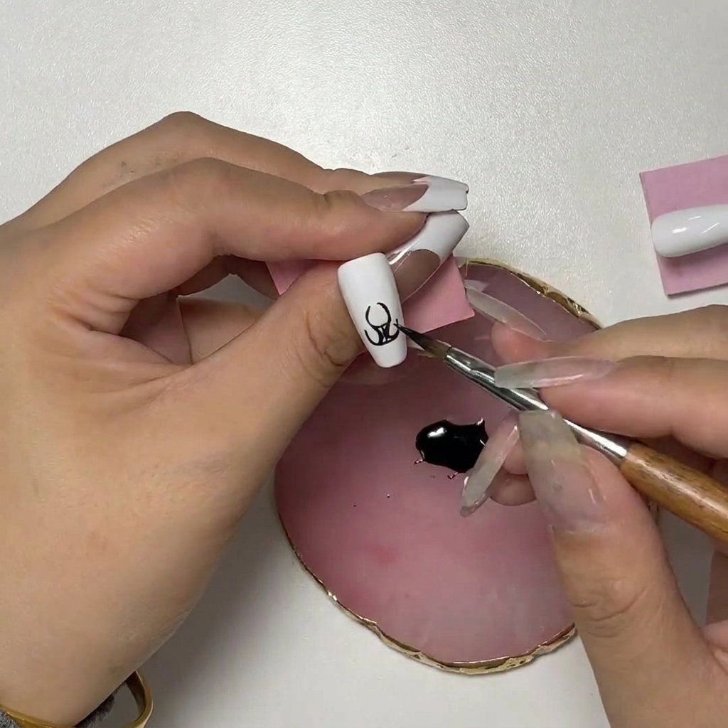 Primo piano della nail art che mostra il pennello che aggiunge tratti ricurvi verso lalto per formare le punte della fiamma.