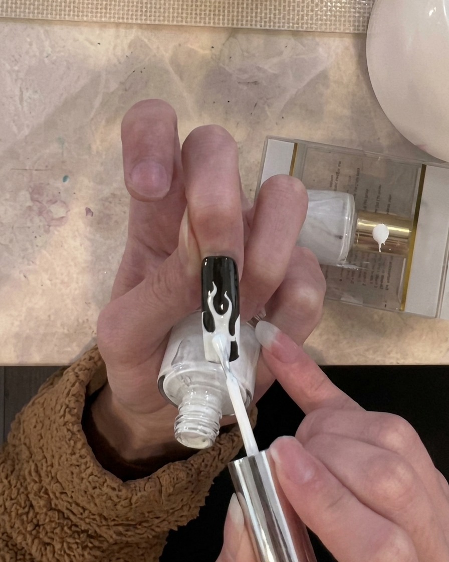 Un pennello applica uno strato di gel bianco solo sulle aree a forma di fiamma sulla punta dellunghia.