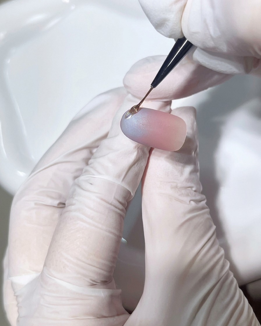Un pennello a punta sottile applica una goccia precisa di gel trasparente denso sullunghia per creare un accento 3D.