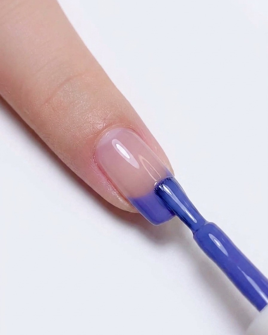 Ri-applicazione dello smalto gel blu e viola sulla punta dellunghia per intensificare la transizione di colore.