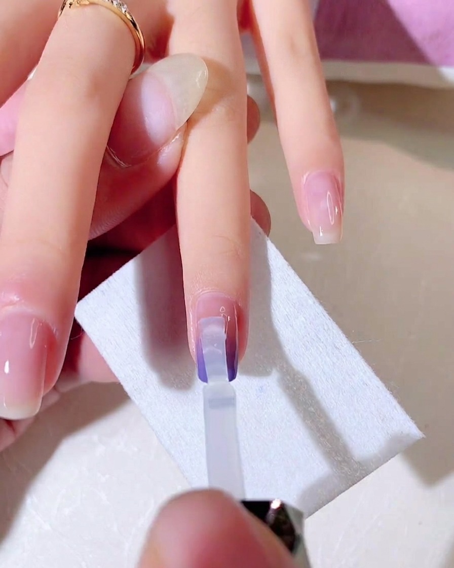 Un pennello in gel trasparente sfuma il secondo strato di colore gradiente verso il basso sullunghia.