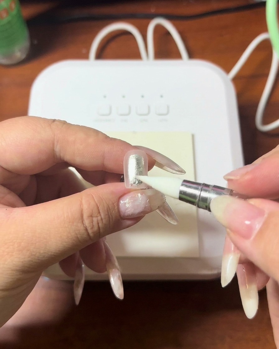 Primo piano di uno strumento in silicone che preme delicatamente sulla punta di ununghia per sfumare il gel.