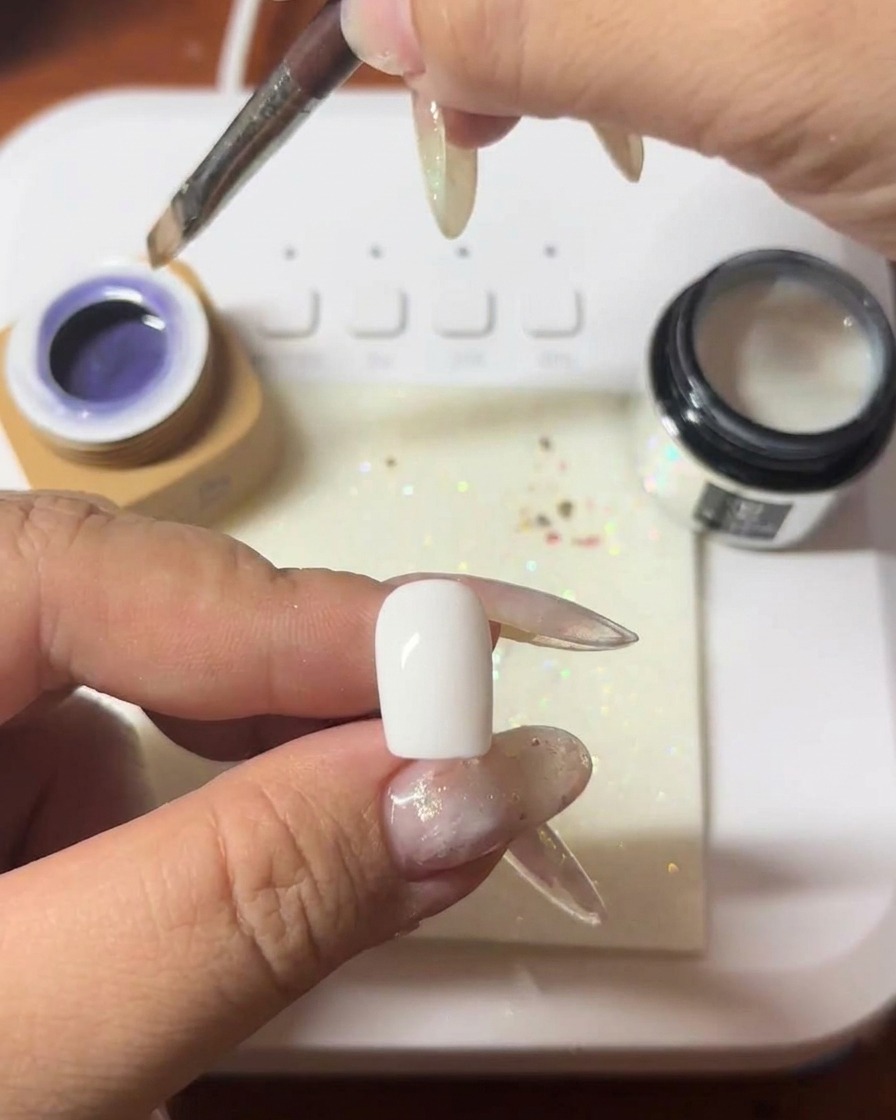 Un pennello che applica uno strato di gel cat-eye viola intenso su ununghia.