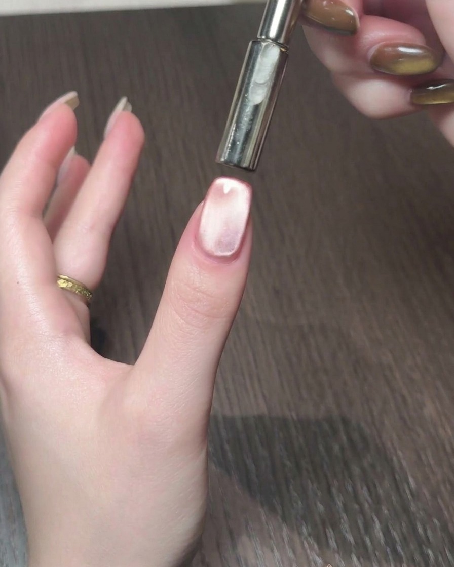 Uno strumento magnetico utilizzato per manipolare i riflessi cat eye in una scia luminosa sullunghia.