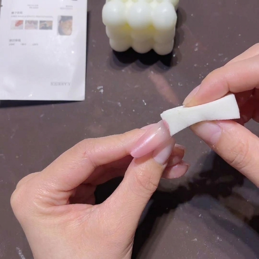 Primo piano di una mano che usa un blocchetto di spugna per tamponare gel pesca-rosa sulla punta di ununghia lunga per creare un effetto sfumato.