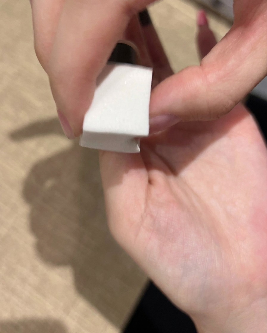 Una spugnetta da trucco utilizzata per picchiettare delicatamente lo smalto gel rosa sullunghia creando una sfumatura morbida.