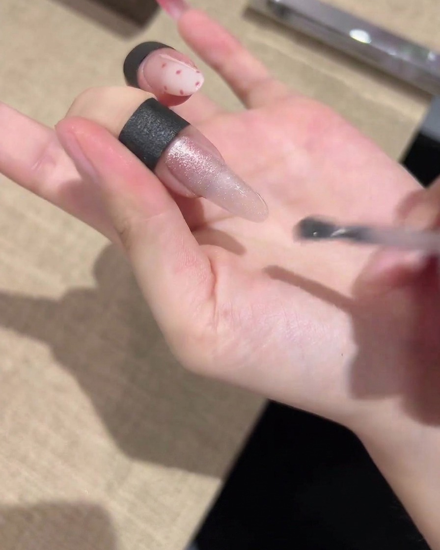 Un pennellino che stende uno smalto gel cat-eye cangiante in modo uniforme su tutta la lunghezza dellunghia.