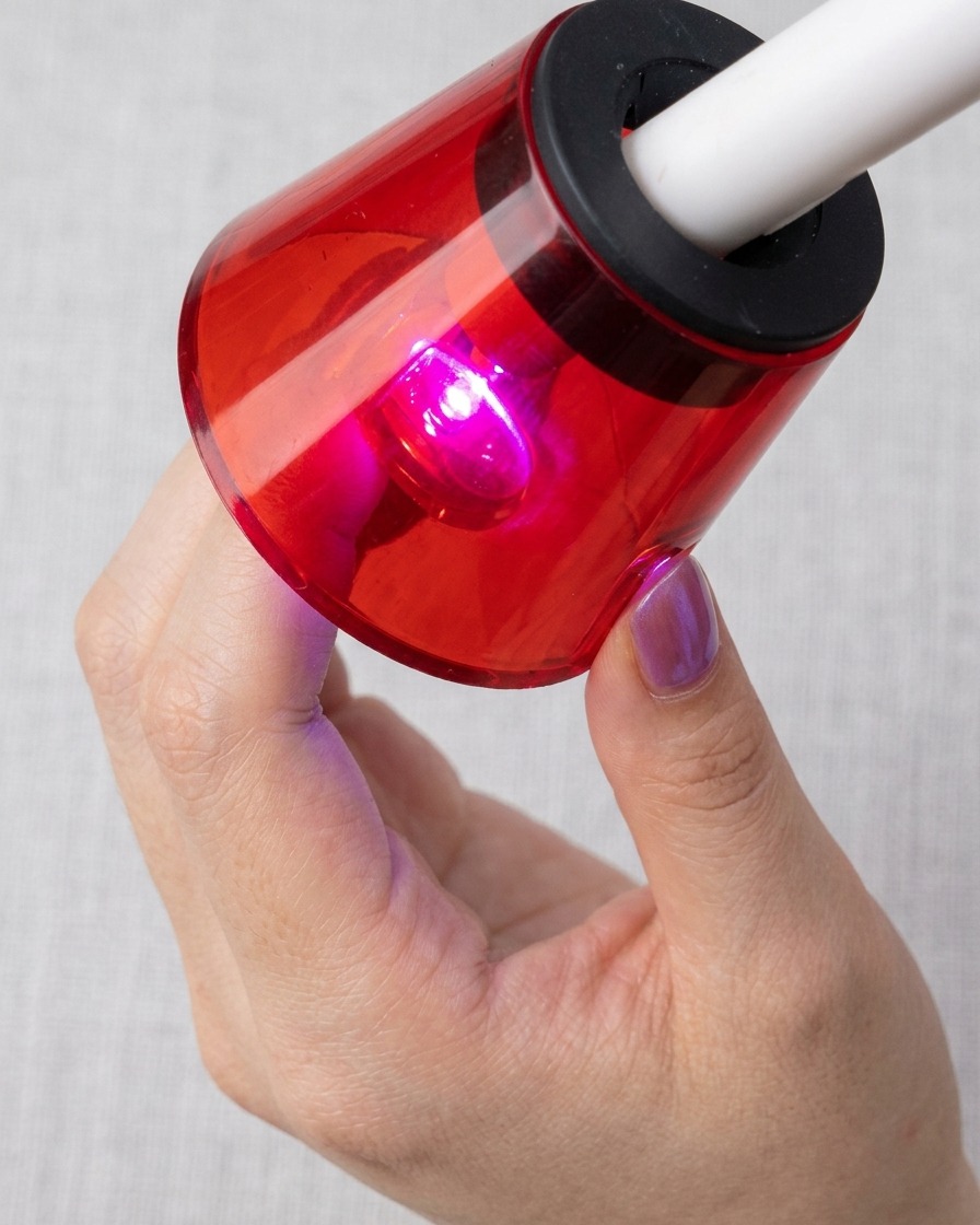 Ununghia posta sotto una lampada UV/LED rossa, in fase di polimerizzazione con le particelle magnetiche del cat-eye ben visibili.