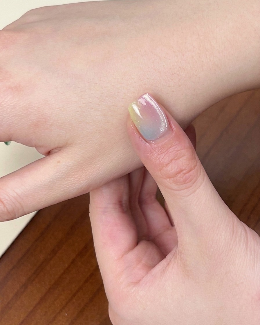 Un primo piano di una mano con la manicure sfumata finita, posizionata allinterno di una lampada UV/LED per unghie con la luce accesa.
