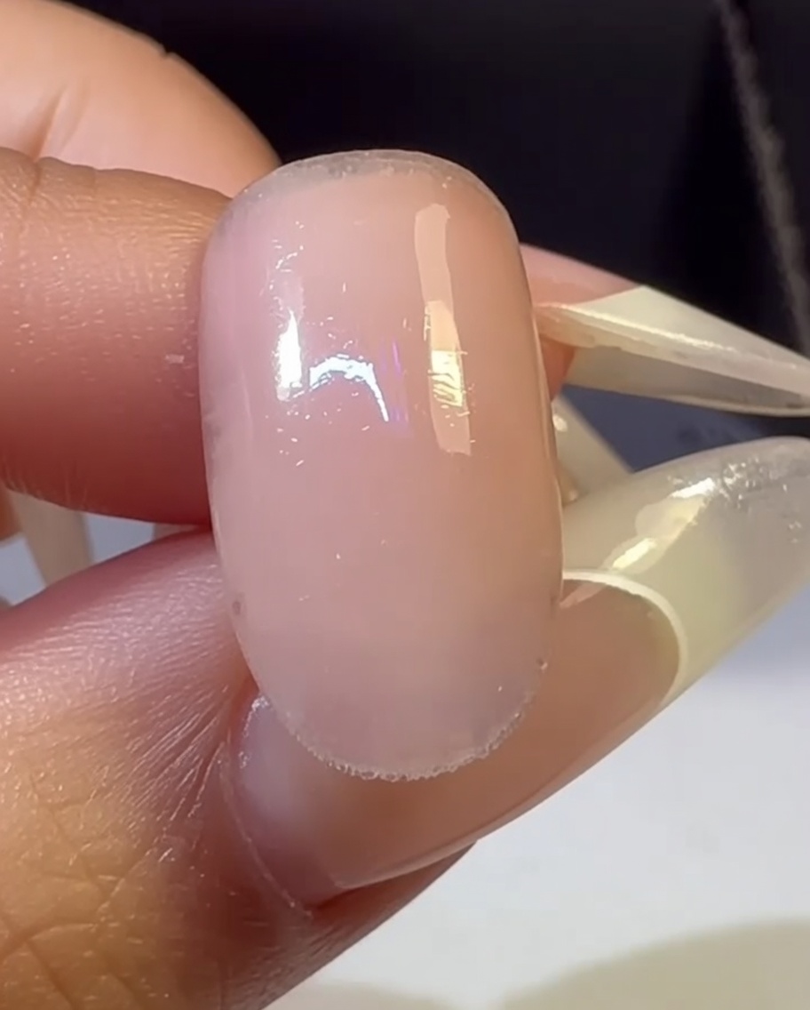 Una mano con ununghia sfumata multicolore allinterno di una lampada UV.