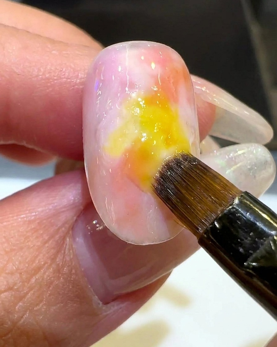 Un pennello applica uno strato sottile di smalto bianco latte lungo il perimetro della sfumatura.