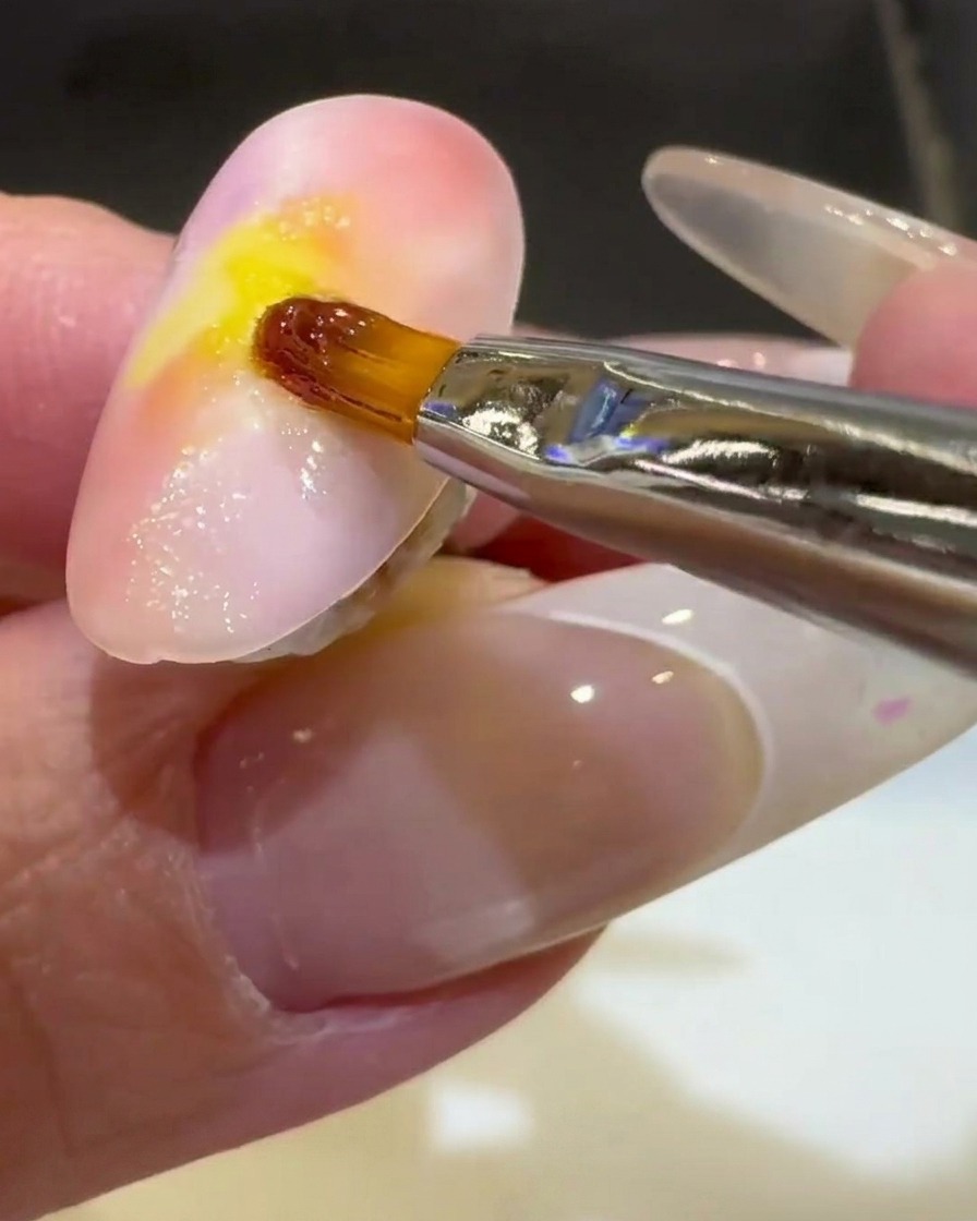 Un pennello liner sottile rifinisce unonda in gel trasparente 3D sulla metà inferiore dellunghia.
