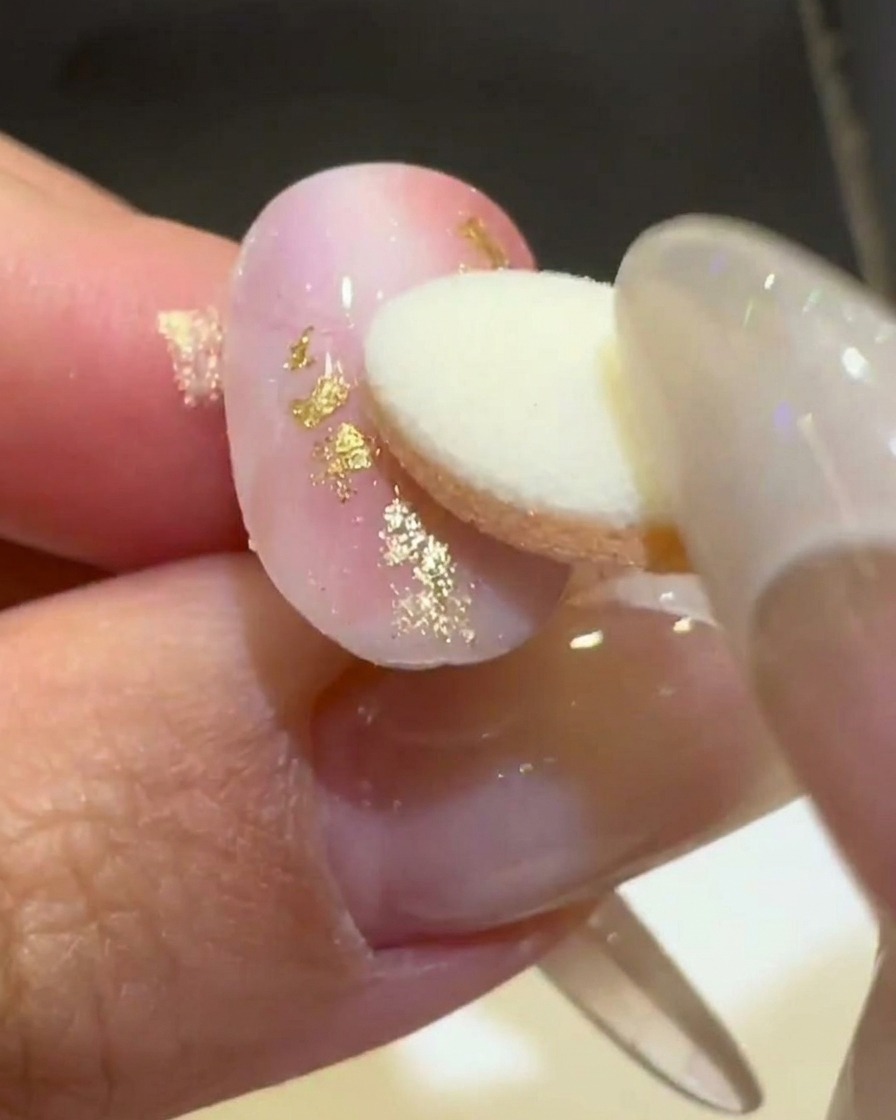 Un applicatore in spugna sfrega la polvere cromata dorata aurora su una linea ondulata 3D rialzata.