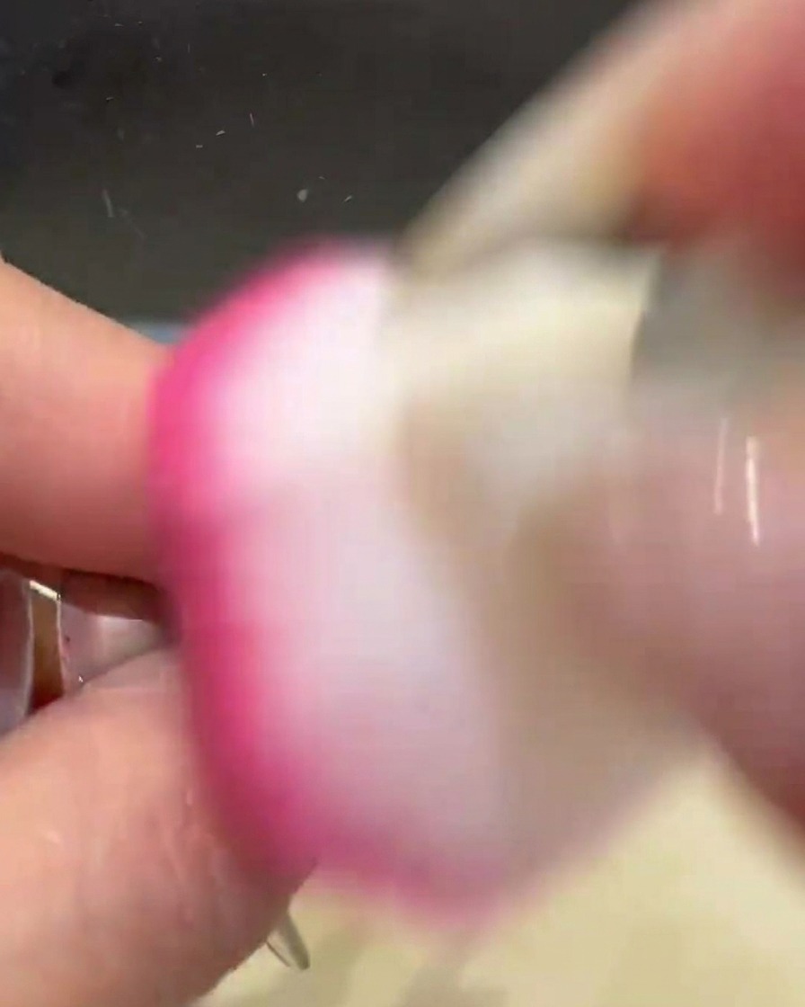 Un pennello spolverino rosa e morbido passa sullunghia per rimuovere leccesso di polvere cromata dorata.
