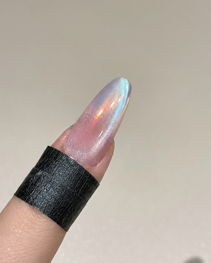 Uno strumento magnetico tenuto vicino al lato di ununghia per manipolare le particelle metalliche nel gel cat eye umido.