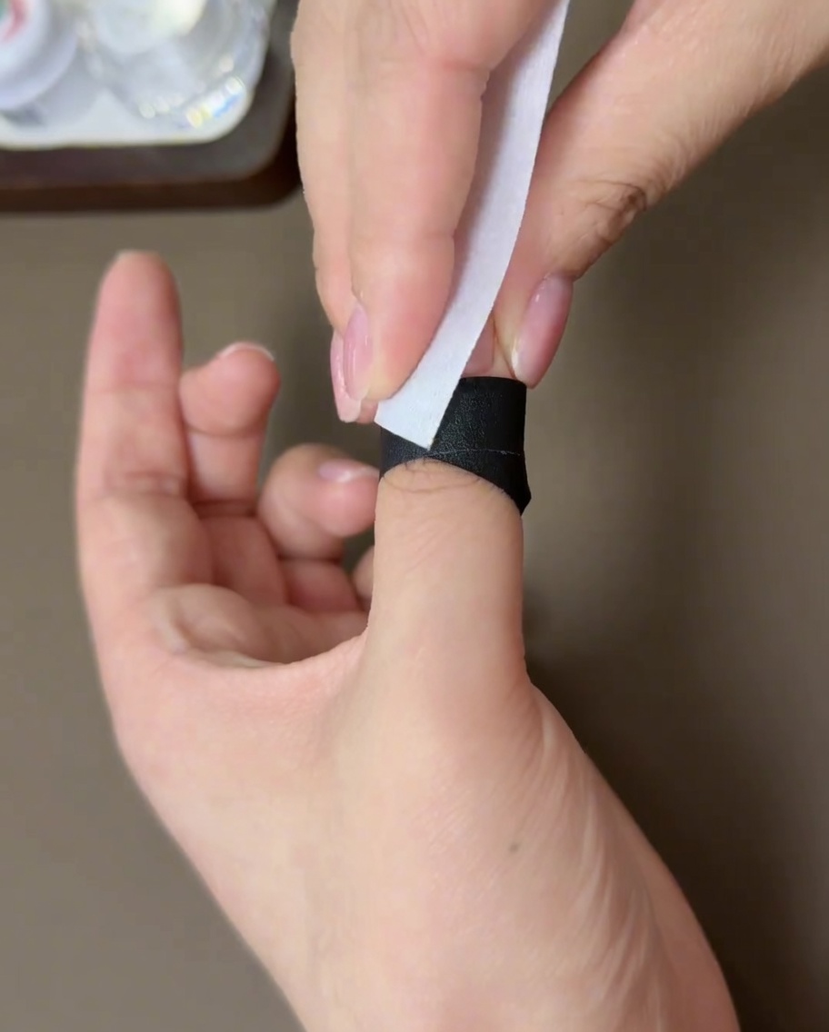 Una salvietta senza pelucchi pulisce la superficie di ununghia in gel polimerizzata.