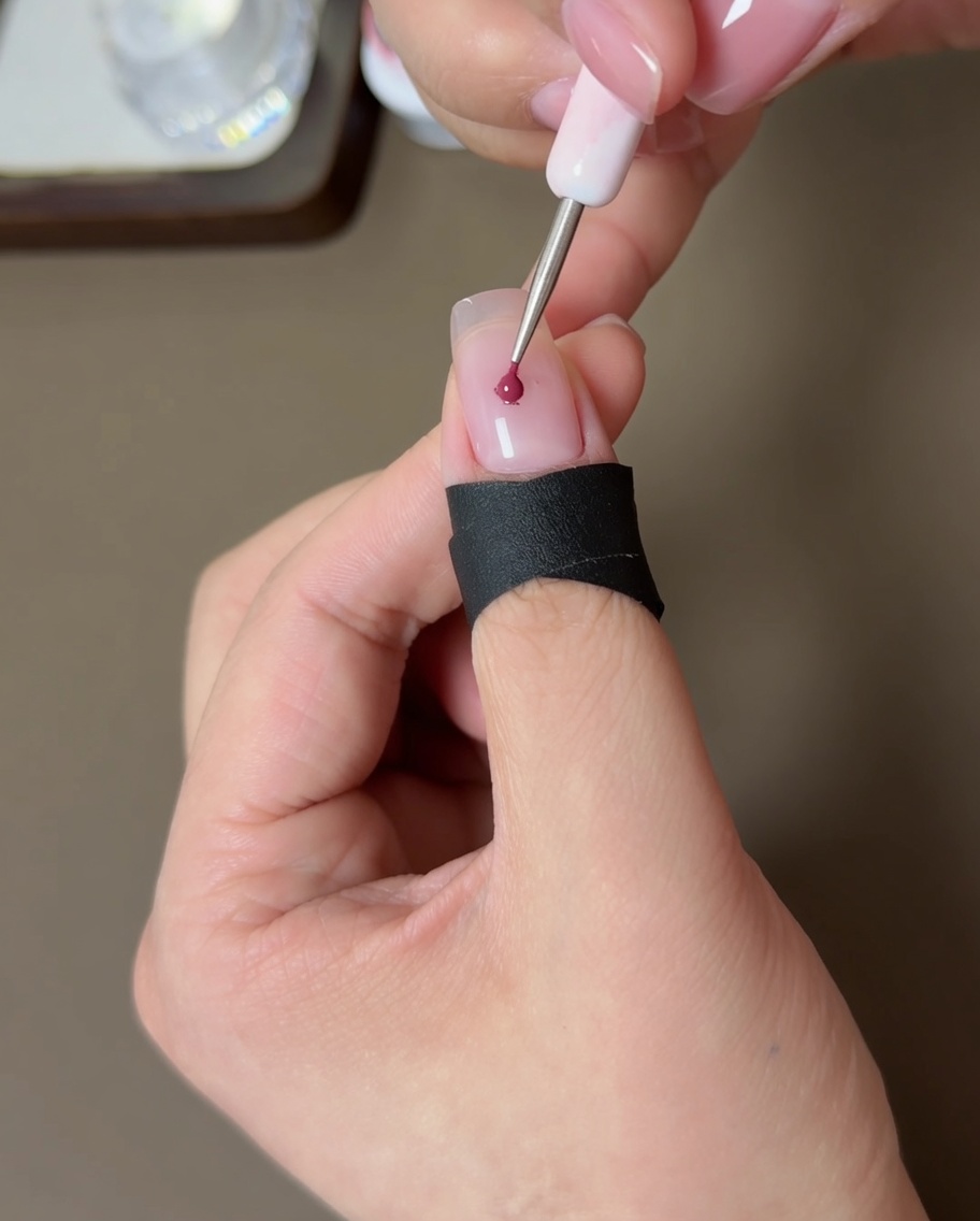 Un piccolo strumento applica un punto di gel pesca al centro di ununghia nude.