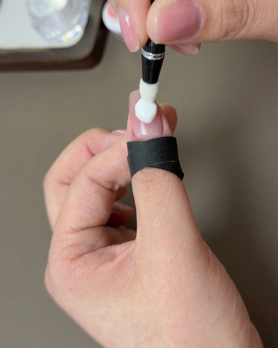 Primo piano di una mano con unghia sfumata pesca che polimerizza sotto una lampada UV professionale.