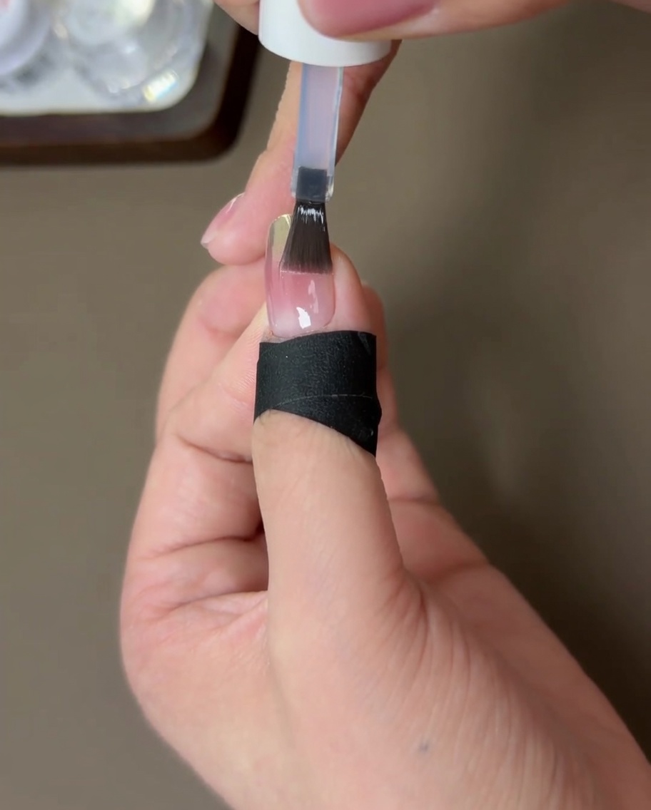 Ununghia rifinita con top coat rinforzante che polimerizza sotto una lampada UV.