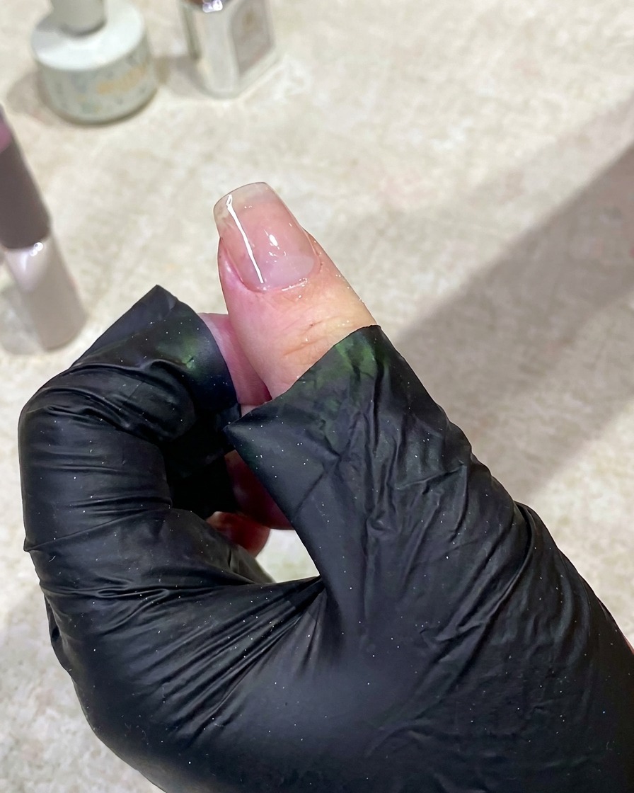 Una mano allinterno di una lampada UV per unghie accesa, che polimerizza la base.