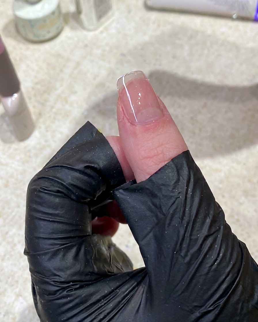 Primo piano di una mano che usa una salvietta priva di lanugine per pulire la superficie di ununghia.