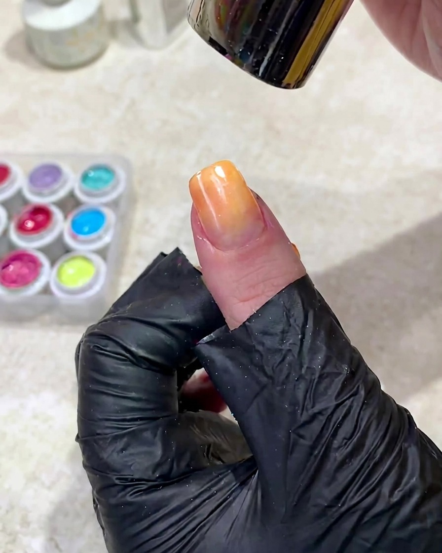 Una mano posizionata sotto una lampada UV per polimerizzare il gel sfumato appena applicato.