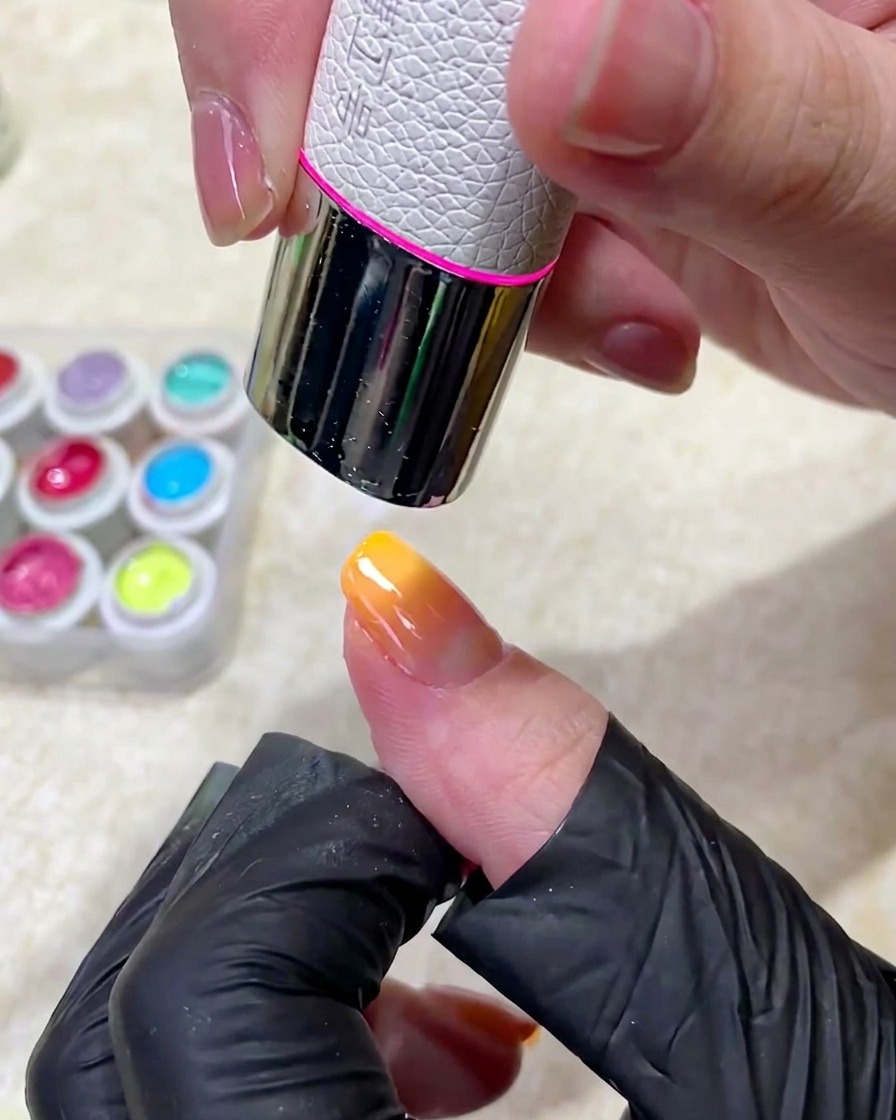 Un dito con manicure posizionato sotto una lampada UV professionale per polimerizzare il gel.