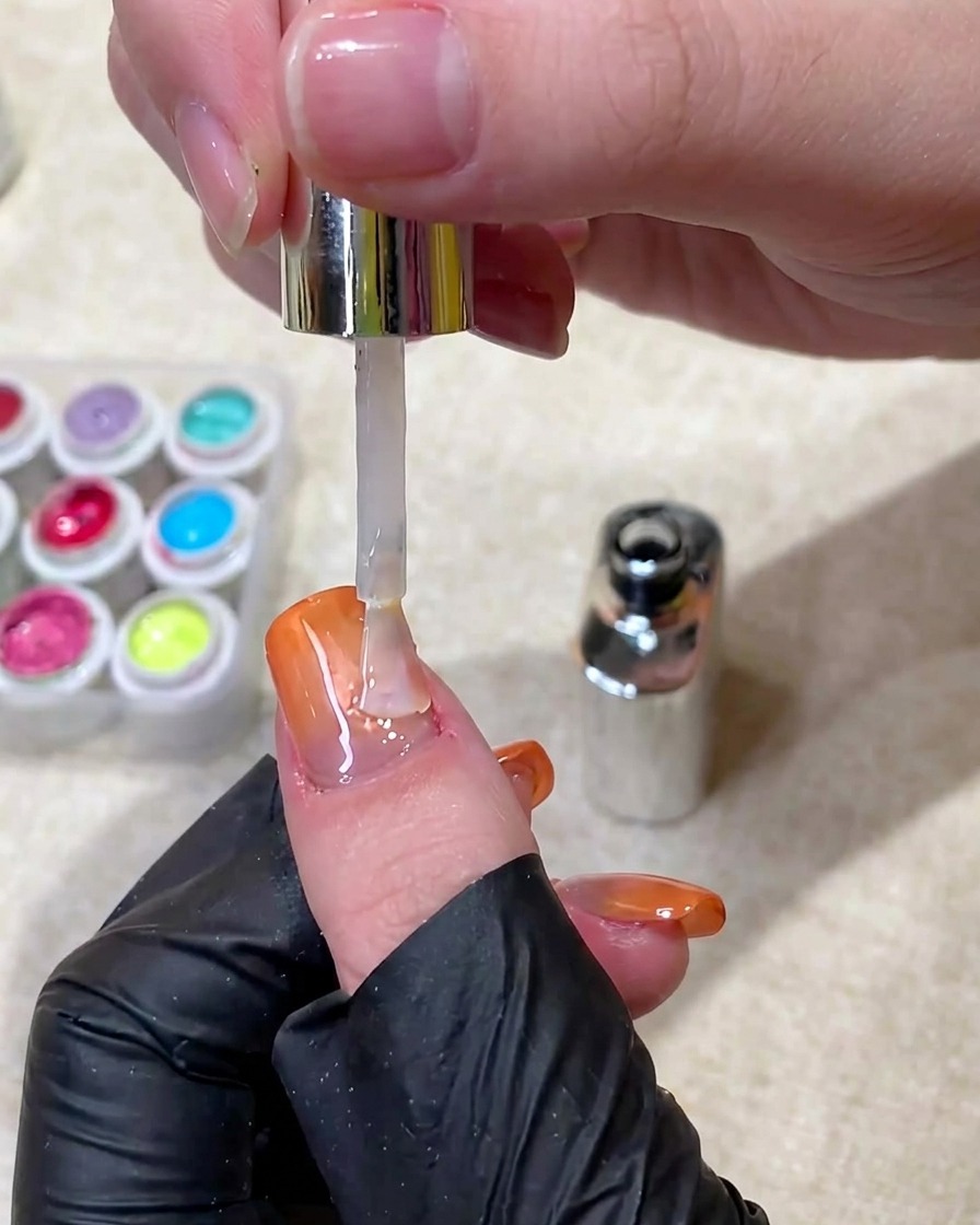 Un pennello che applica un top coat trasparente e lucido sopra ununghia finita.