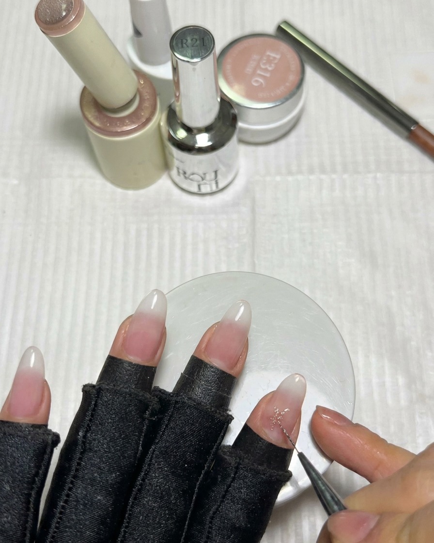 Un pennello liner sottile riempie il centro di una stella in gel rosa sullunghia per creare punte affilate.