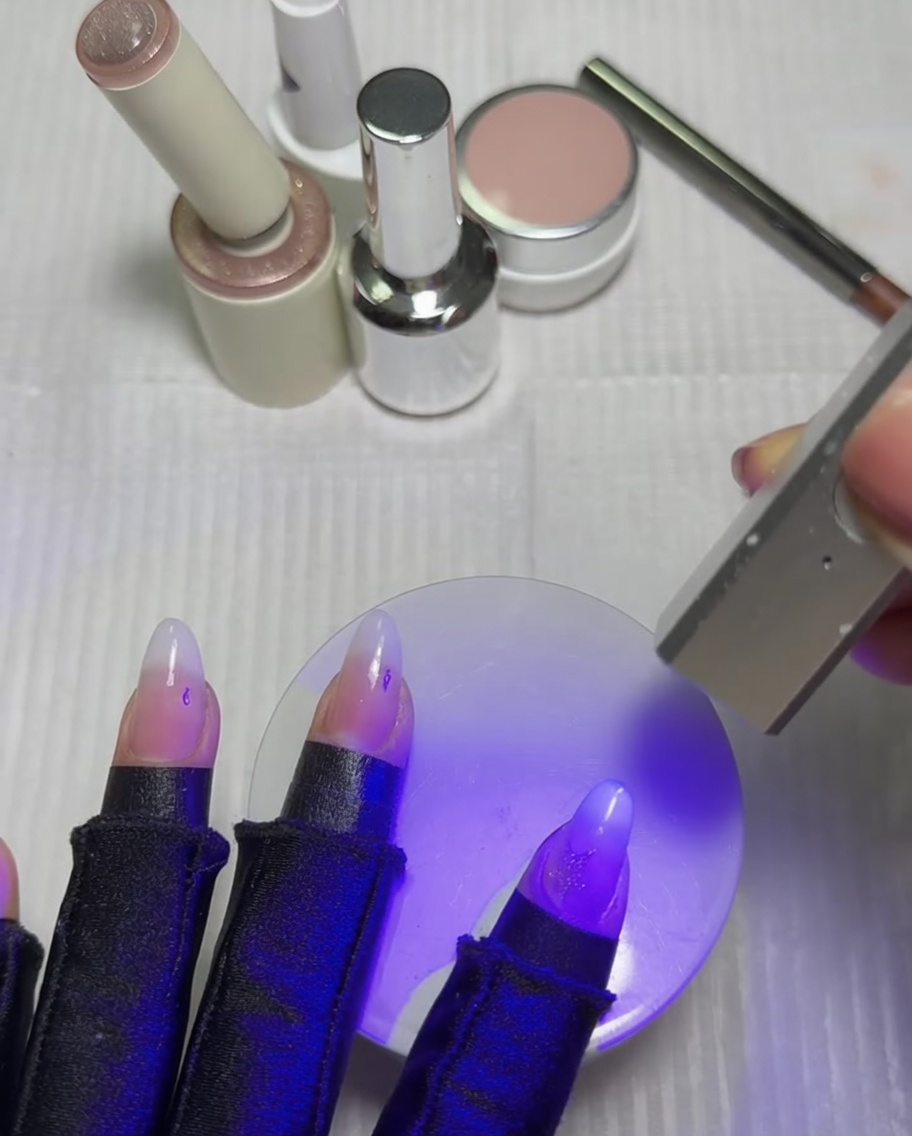 Unghie che riposano sotto una lampada UV e LED viola per polimerizzare la stella cat-eye appena attivata.