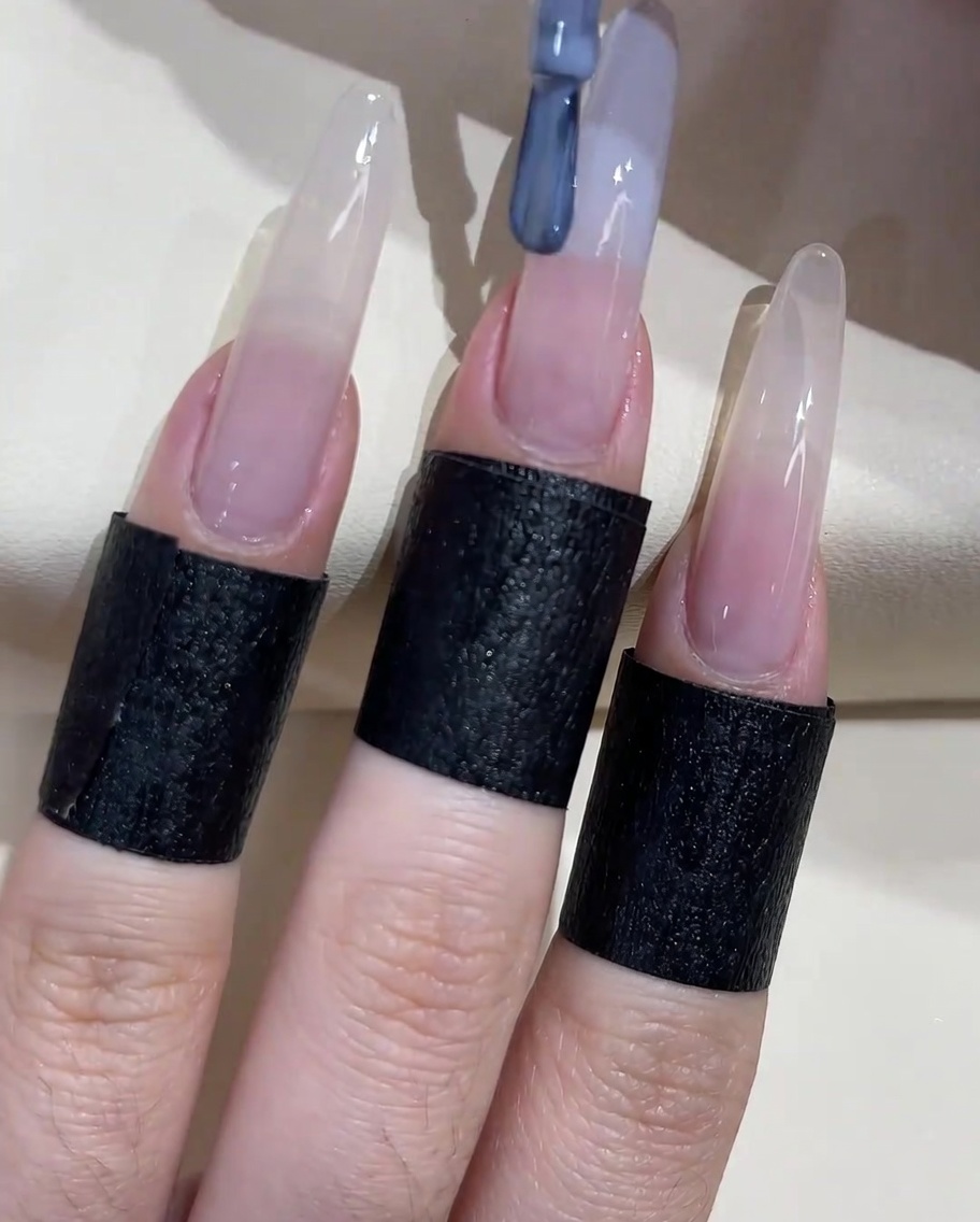 Un pennello per unghie che applica uno smalto gel grigio-blu sul bordo libero dellunghia.