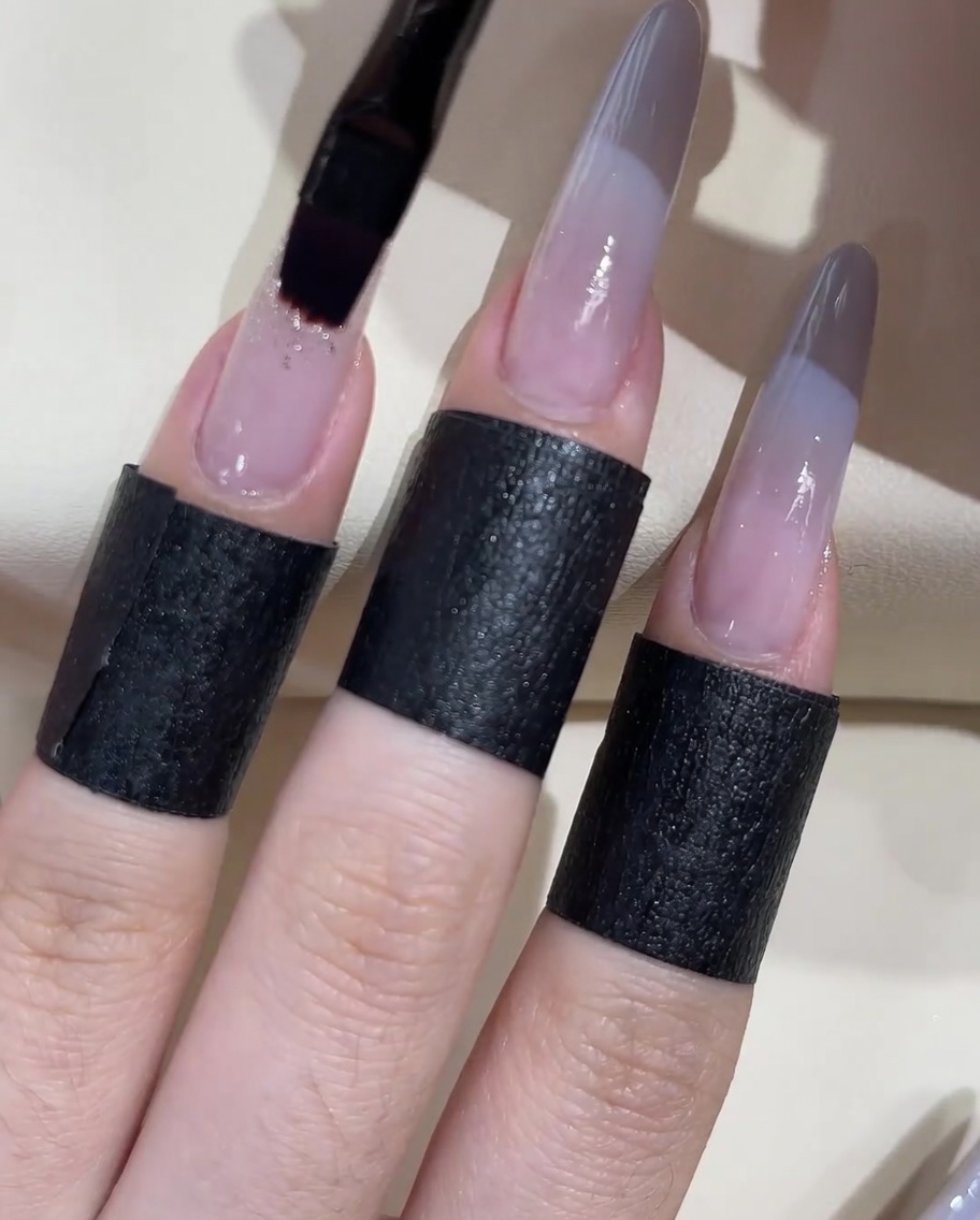 Un pennello piatto per gel che applica una goccia di gel adesivo trasparente denso sulla superficie di ununghia.