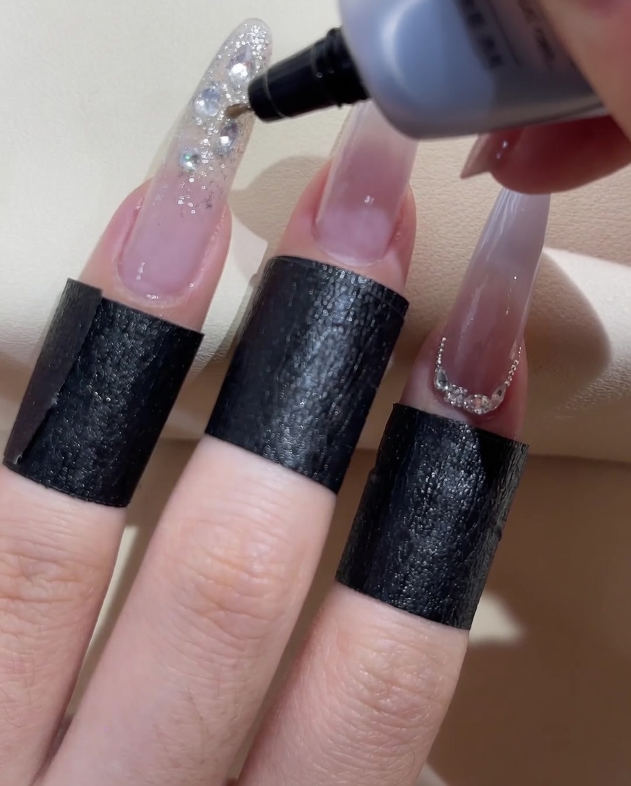 Una boccetta di gel a punta fine che applica gel sigillante trasparente attorno ai bordi degli strass decorativi.