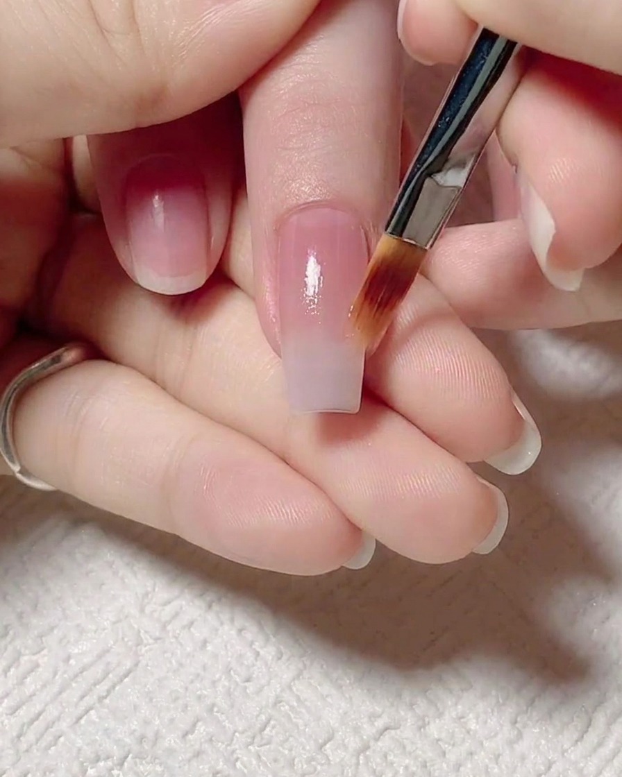 Un pennello piatto che stende delicatamente la base jelly rosa verso lalto per creare un soffice gradiente di colore.