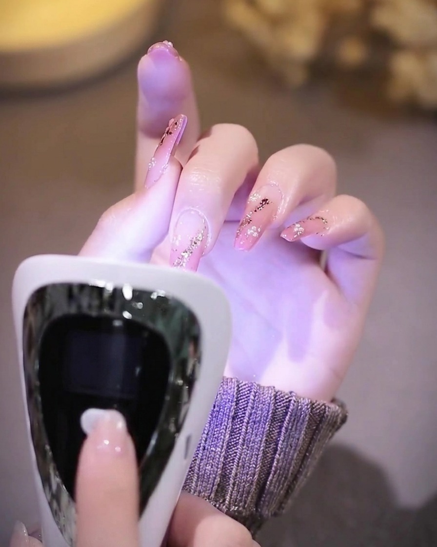 Una mano con unghie finite che riposa allinterno di una lampada UV viola.