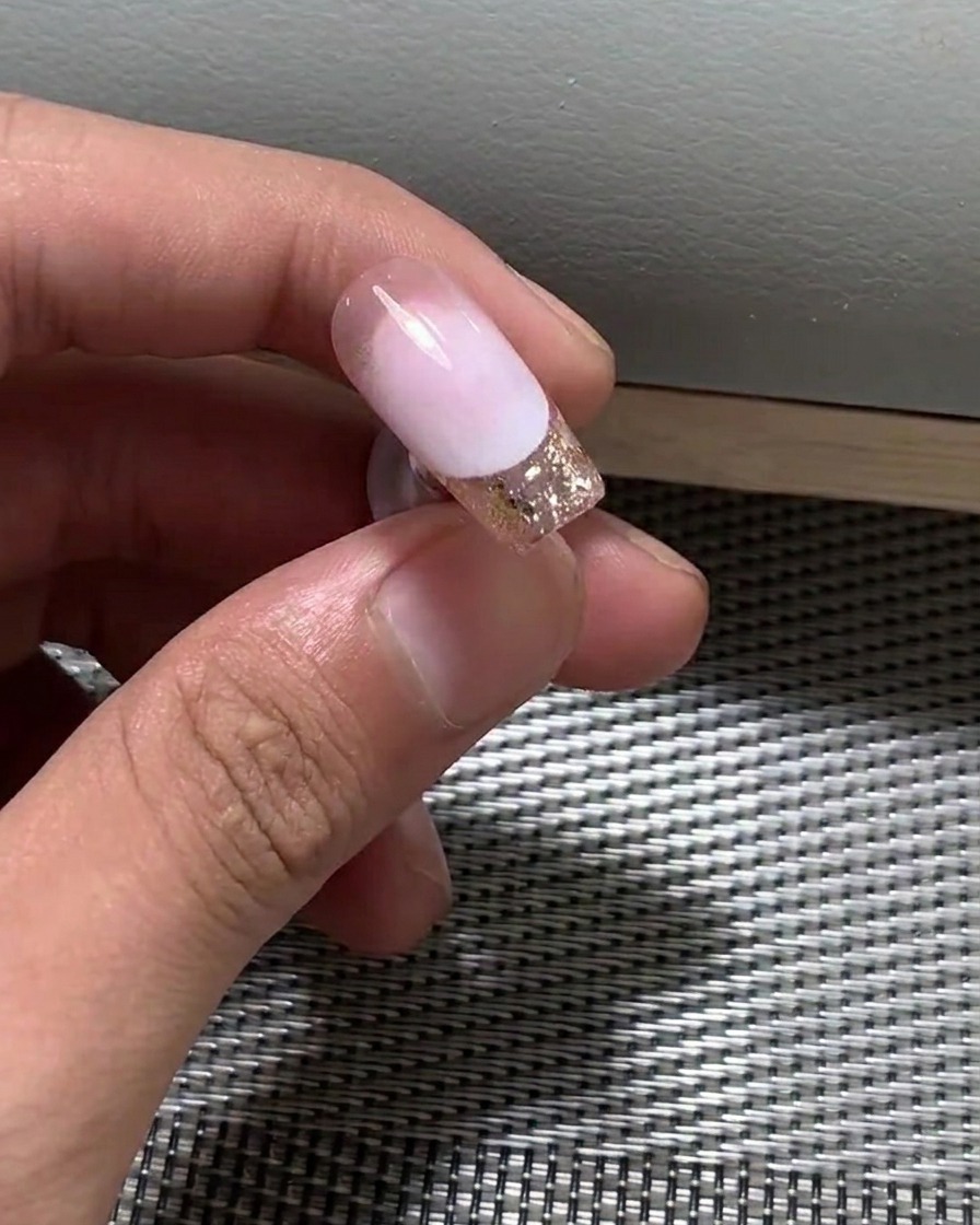Primo piano di un pennello che applica uno strato sottile di smalto gel nude sullunghia.