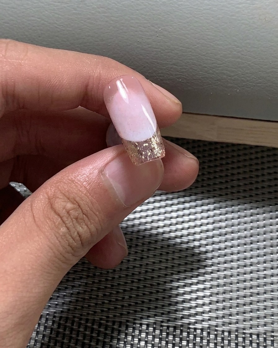 Primo piano di un pennello che applica il secondo strato di smalto gel nude sullunghia.