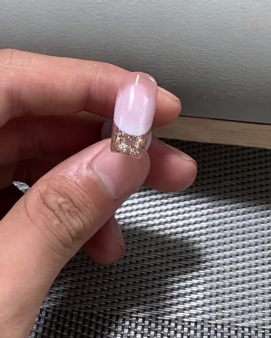 Una mano posizionata sotto una lampada UV professionale per polimerizzare lo smalto gel.