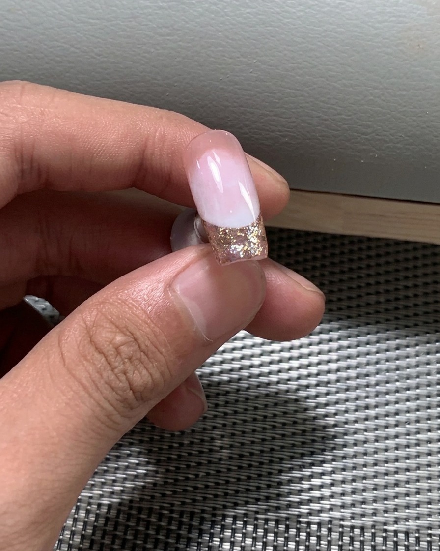 Primo piano di smalto glitterato applicato sul bordo libero dellunghia.