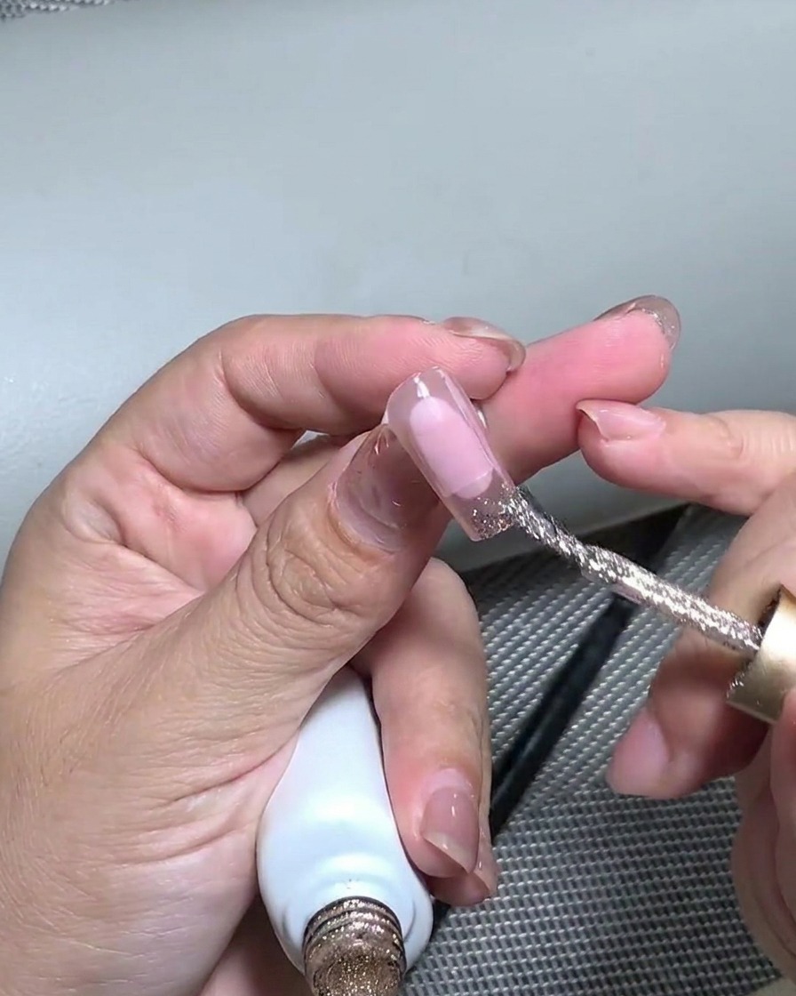 Uno strumento in silicone che preme sulla foglia oro applicata sulla punta dellunghia per appiattirla.
